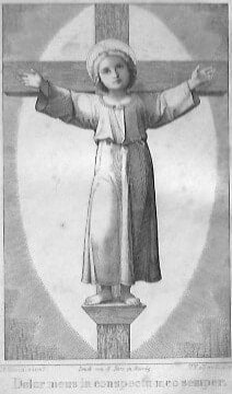 Das Jesukind steht auf einem Holzpodest, an dem ein Holzkreuz ist; das Christuskind hält die beiden Arme ausgebreitet am Kreuz