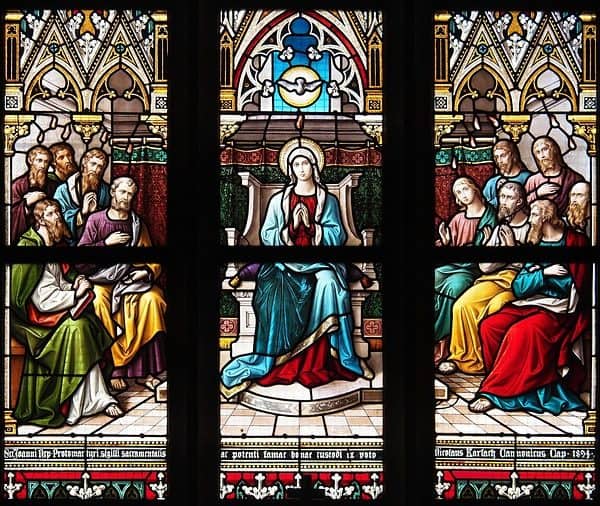 Die Herabkunft des Heiligen Geistes an Pfingsten: Ein wunderschönes Glasfenster des Pfingstereignisses: Die Gottesmutter Maria sitzt auf einem Thron in der Mitte, der Heilige Geist als Taube über ihr; rechts und links von ihr sitzen die Apostel wie Maria in betender Haltung