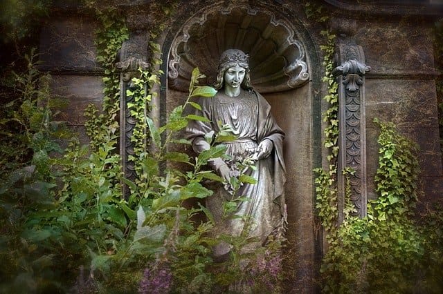 An der Friedhofsmauer, von Efeu umrankt, steht ein Engel, schön gekleidet, und schaut auf die Verstorbenen, deren Seelen in der Ewigkeit sich befinden