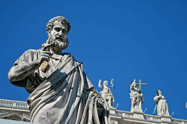 Statue von Petrus, dem ersten Papst, mit dem Schlüssel in der Hand, im Hintergrund der auferstandene Christus sowie zwei Heilige