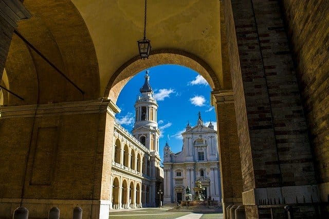 Die Basilika von Loreto mit dem schlanken Turm ist aus der Perspektive eines großen Torbogens zu sehen