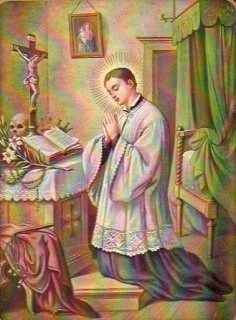 Der Heilige kniet in seinem Zimmer vor dem Altar, die Hände gefaltet, vor ihm das Kruzifix und fas Messbuch; an der Wand hängt ein Muttergottesbild