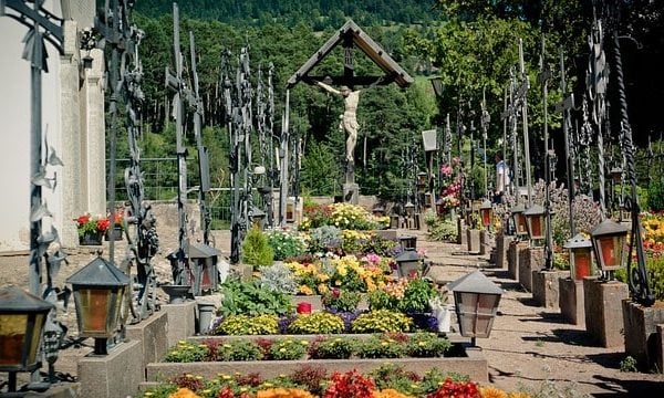 Ein Kirchhof mit Gräbern und vielen Kreuzen aus Eisen; in der Mitte im Hintergrund ein hölzernes großes Kruzifix; dies erinnert uns an Tod und Gericht